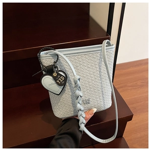 Gros plan du sac seau tressé bleu clair avec détails de texture et breloques cœur