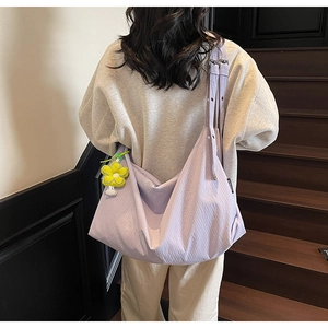 Detail of light purple pleated fabric shoulder bag featuring a yellow sunflower pendant