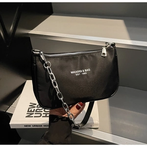 Minimalist black nylon shoulder bag detail featuring brand print and silver chain