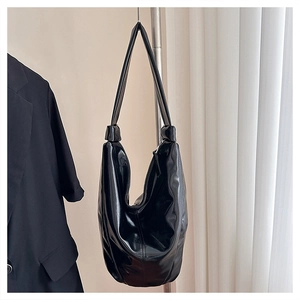Détail du sac hobo en similicuir noir brillant avec fermeture éclair et bandoulière large