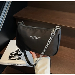 Close-up of black crescent shoulder bag with silver chain and white logo on nylon fabric