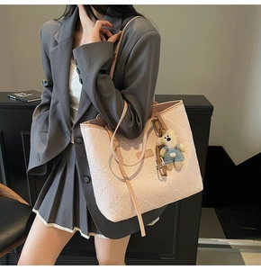 Détail d'un sac cabas floral rose pâle avec breloque ours porté par un mannequin