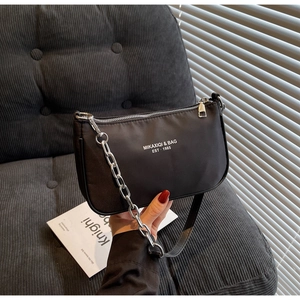 Close-up of black nylon shoulder bag featuring silver metal chain and 1985 text detail