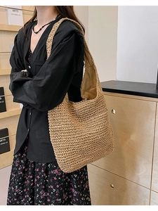Large khaki straw tote bag with woven shoulder strap shown in a minimalist home setting