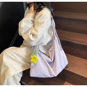 Close-up of a lavender tote bag with textured nylon fabric and a yellow floral charm