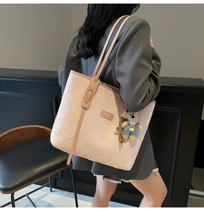 Détail du cabas en tweed rose avec lanières en cuir et un joli charm en forme d'ours