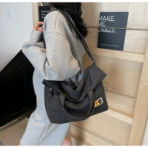Detail of black canvas tote bag with cartoon embroidery and dual-handle design