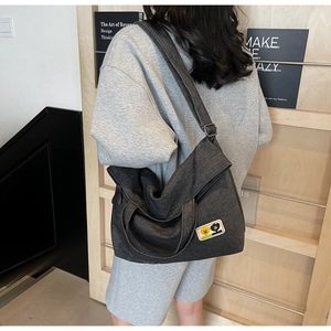 Detail of dark gray canvas tote bag with cartoon patch on warm wood background