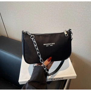Close-up of black nylon shoulder bag with silver chain detail and white logo print