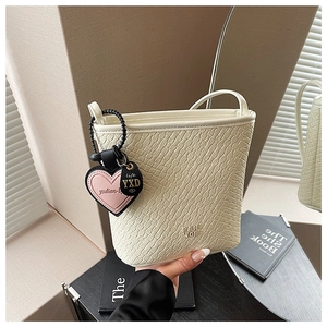 Détail du sac seau blanc crème avec gaufrage crocodile et pendentif cœur rose