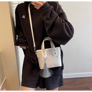 Détail d'un sac à main blanc crème avec broderie ethnique et pompon décoratif gris