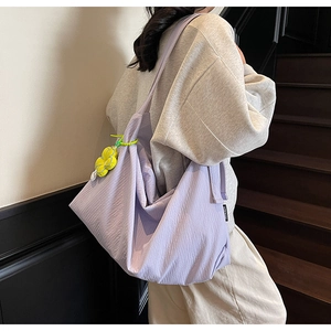 Detail of light purple shoulder bag with yellow flower charm on minimalist background