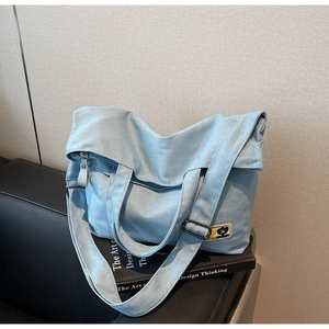 Detail of light blue canvas tote bag with adjustable strap and small cartoon patch