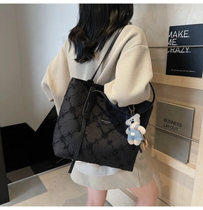 Détail du sac cabas noir avec paillettes matelassées et charm ours en jean sur l'épaule