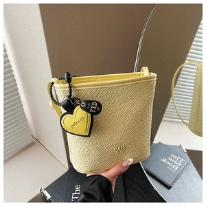 Détail du sac seau jaune clair avec texture crocodile et breloque en forme de cœur