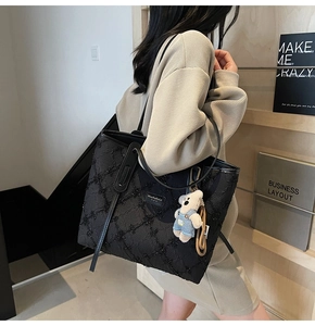 Détail du grand sac cabas noir à paillettes avec anses en cuir et breloque ours en peluche