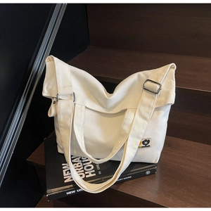 Detail shot of the sturdy white canvas tote bag with adjustable nylon straps and embroidery