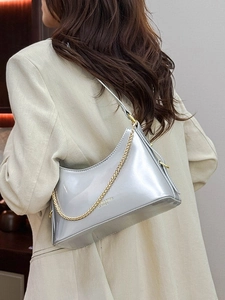 Silver metallic shoulder bag with gold chain strap shown on a model in a minimal setting