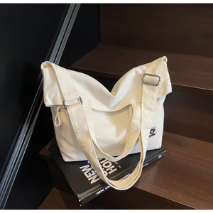 Detail of vintage beige canvas tote bag showing stitching and logo on wooden stairs