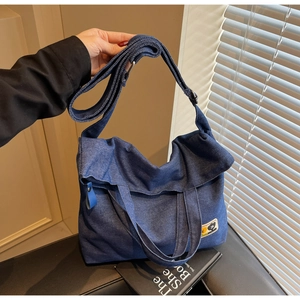Close-up of a vintage dark blue denim tote bag with functional double straps and patch