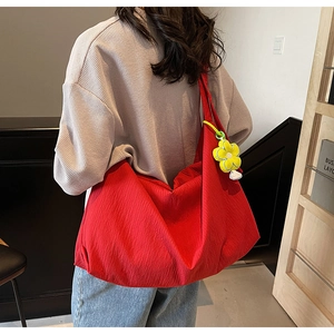 Detail of red oversized shoulder bag with bark texture and yellow flower charm