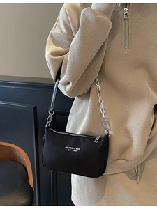 Fashionable black nylon shoulder bag with silver chain strap shown on a model