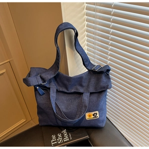 Macro detail of dark blue denim tote bag featuring floral patches and silver hardware
