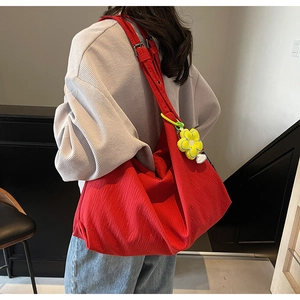 Detail of red large capacity shoulder bag with unique fabric texture and yellow flower charm