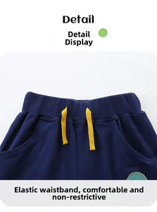 Detail of elastic waistband on navy blue kids' shorts with yellow drawstring and ribbing