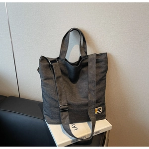 Close-up of a vintage dark grey canvas tote bag with functional pockets and long straps