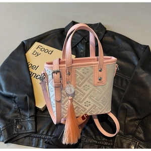 Détail du sac seau rose avec motifs vintage, longues pampilles et boucles métalliques fines