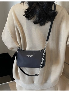 Black nylon shoulder bag with silver chain and artistic text print on model