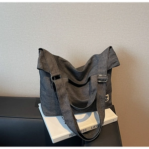 Close-up of charcoal gray denim tote bag showing metal buckle and fabric texture