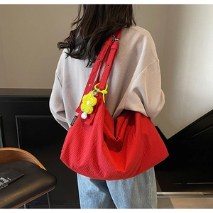 Detail of red oversized tote bag with pleated texture and yellow flower charm
