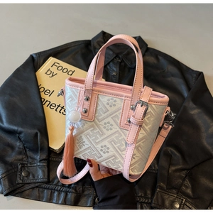 Gros plan du sac seau en cuir rose avec motif jacquard et détail de pompon
