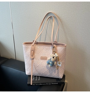 Détail du sac cabas rose montrant la texture gaufrée et un charmant ours en peluche