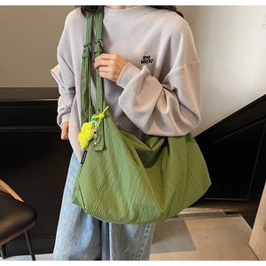 Detail of green tote bag with pleated texture and yellow flower charm on shoulder