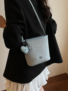 Sac seau tressé bleu clair avec fine bandoulière en cuir et breloque en forme de cœur