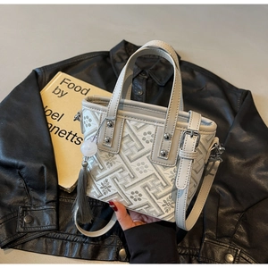 Détail d'un mini sac seau tissé avec motif jacquard géométrique et pompon élégant