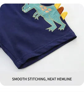 Detailed view of kids' navy knit shorts featuring green dinosaur embroidery and neat hem stitching