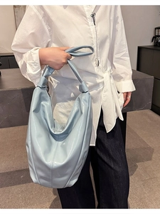 Sac hobo bleu clair brillant avec poignée nouée présenté par un mannequin en intérieur