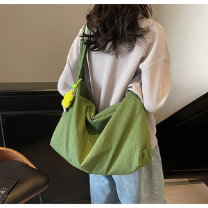 Macro view of green polyester shoulder bag with wide strap and yellow smile charm