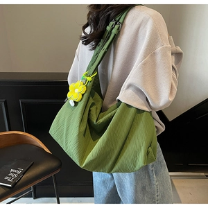 Green shoulder bag with wrinkled fabric and yellow flower pendant on model