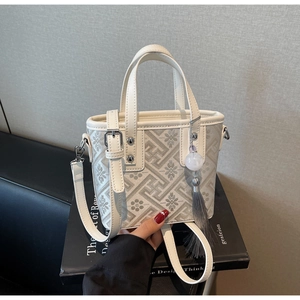 Détail du sac seau blanc avec broderie florale et pendentif à pompon gris élégant