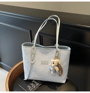 Détail du sac cabas bleu clair avec texture florale et adorable ours en peluche