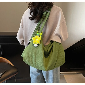 Detail of green hobo bag with pleated fabric texture and yellow flower charm decoration