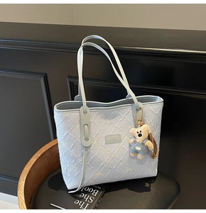 Détail du cabas en jacquard bleu clair avec broderie nœud et breloque en forme d'ours