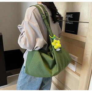 Detailed texture of green nylon shoulder bag featuring a yellow flower charm and wide strap