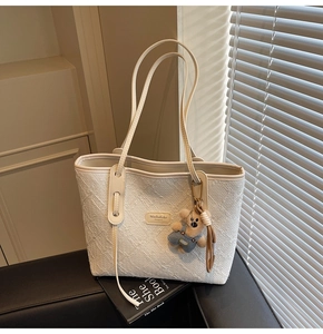 Détail du grand sac cabas crème avec texture tissée et petit ours accessoire