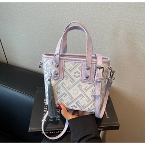 Vue détaillée du sac seau brodé violet avec motifs géométriques et pendentif à pompon